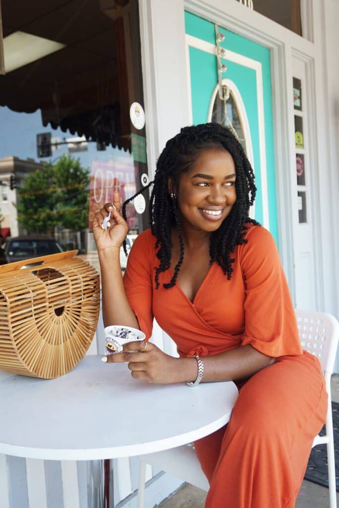 Happy woman sitting outside with ice cream in a cup