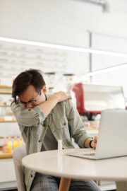 Man sneezing into arm in a deli