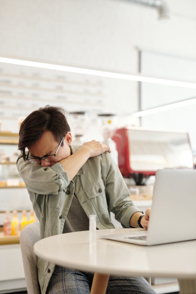 Man sneezing into arm in a deli