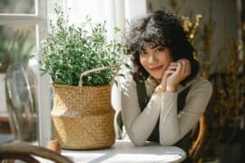 Woman sitting at a table with a plant in a basket