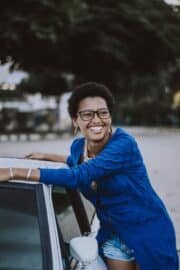 Happy woman leaning on a car
