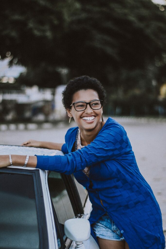Happy woman leaning on a car